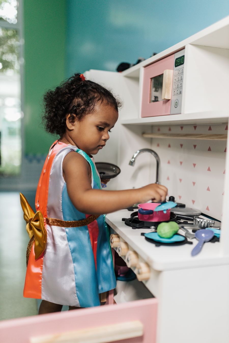 Criança brincando de faz de conta em uma cozinha de brinquedo